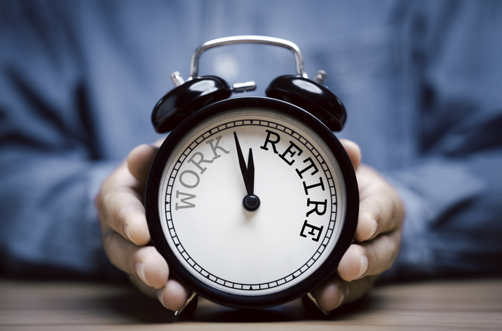 A businessman holding a black alarm clock with clockwise countdown from work to retirement.