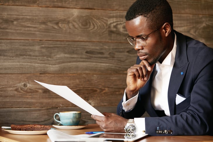 African American man in a suit studying a document